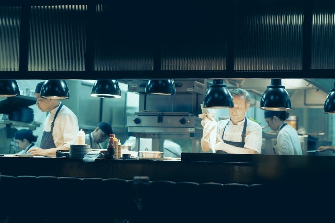 Brigade de cuisine travaillant derrière un comptoir sous des lampes chauffantes